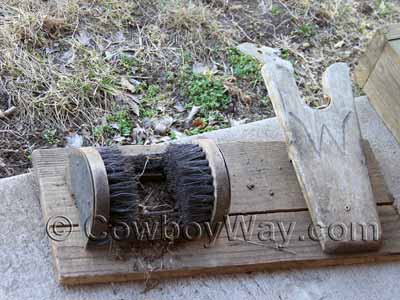 A well-used wooden boot scraper with boot puller and brushes