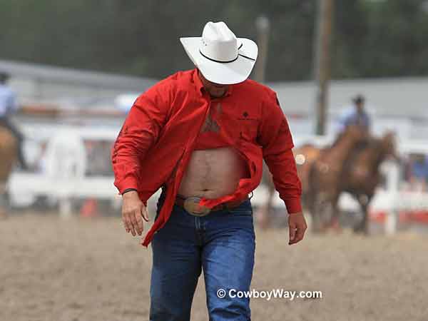A steer wrestler in a torn shirt