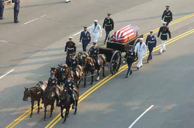 A horse drawn caisson with a flag-covered casket