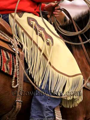 A pair of cowboy chinks on a mounted cowboy