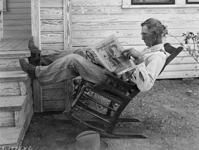 An old farmer reads a farming magazine