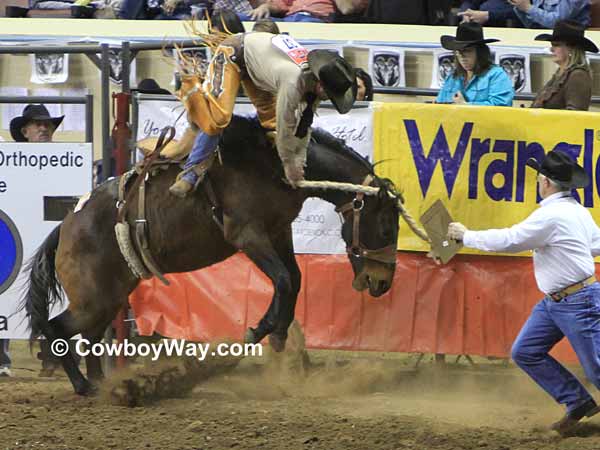 A rider makes a sudden dismount in the saddle bronc riding