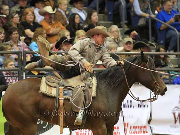 A team member throws his rope from his saddle and dismounts