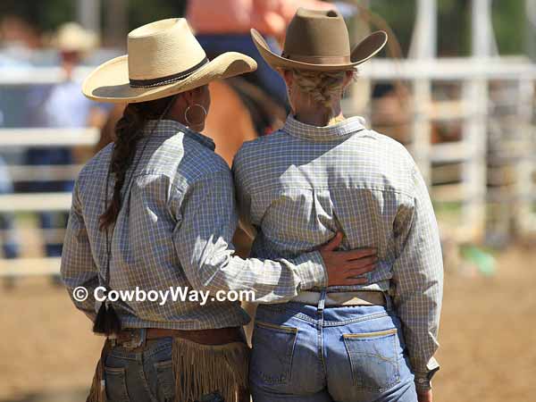 Two cowgirls watch the calf branding at a women's ranch rodeo